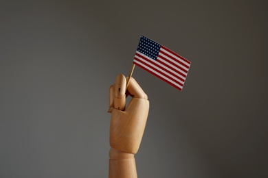 Wooden hand holding flag of USA on dark grey background