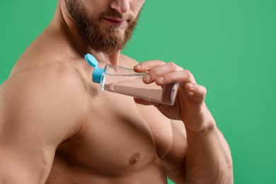 Photo of Man applying lotion onto his shoulder on green background, closeup