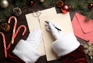 Top view of Santa writing letter at wooden table, closeup