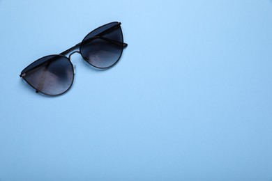 Photo of Stylish sunglasses on light blue background, top view. Space for text