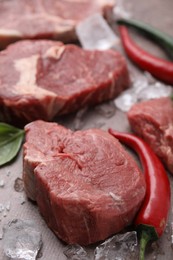 Fresh raw cut beef, ice cubes and spices on brown table, closeup