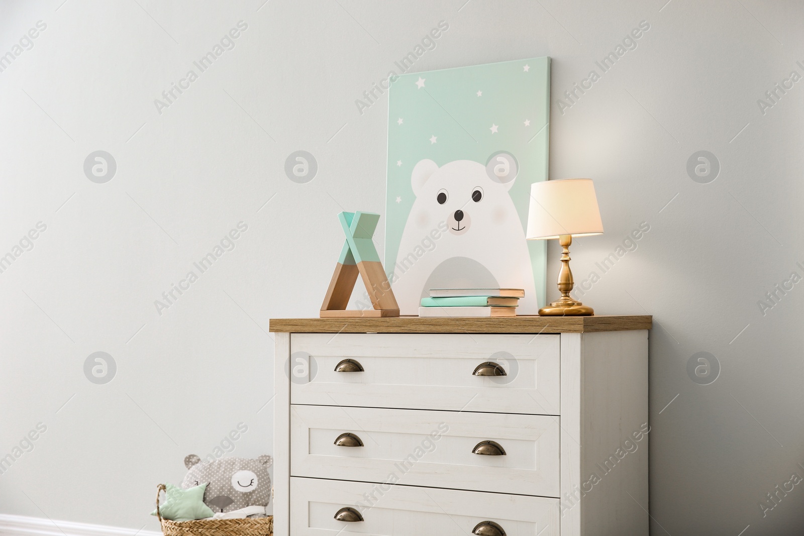 Photo of Modern white chest of drawers near light wall in child room. Interior design