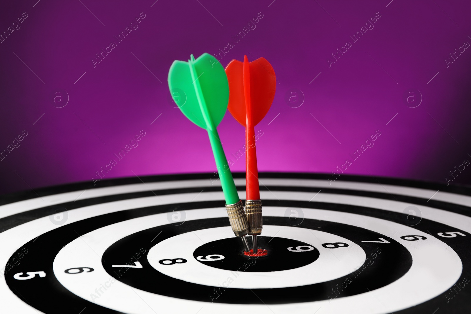 Photo of Arrows hitting target on dart board against purple background