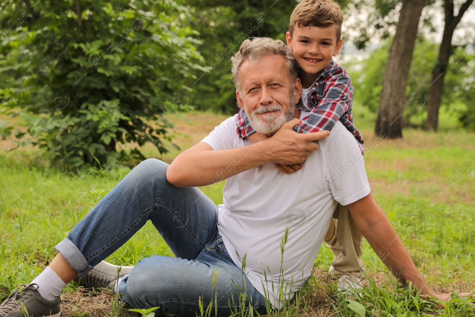 Photo of Cute little boy and grandfather spending time together in park