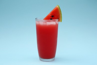 Delicious drink with ice cubes and piece of fresh watermelon on light blue background