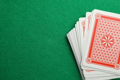 Photo of Deck of playing cards on green table, top view. Space for text