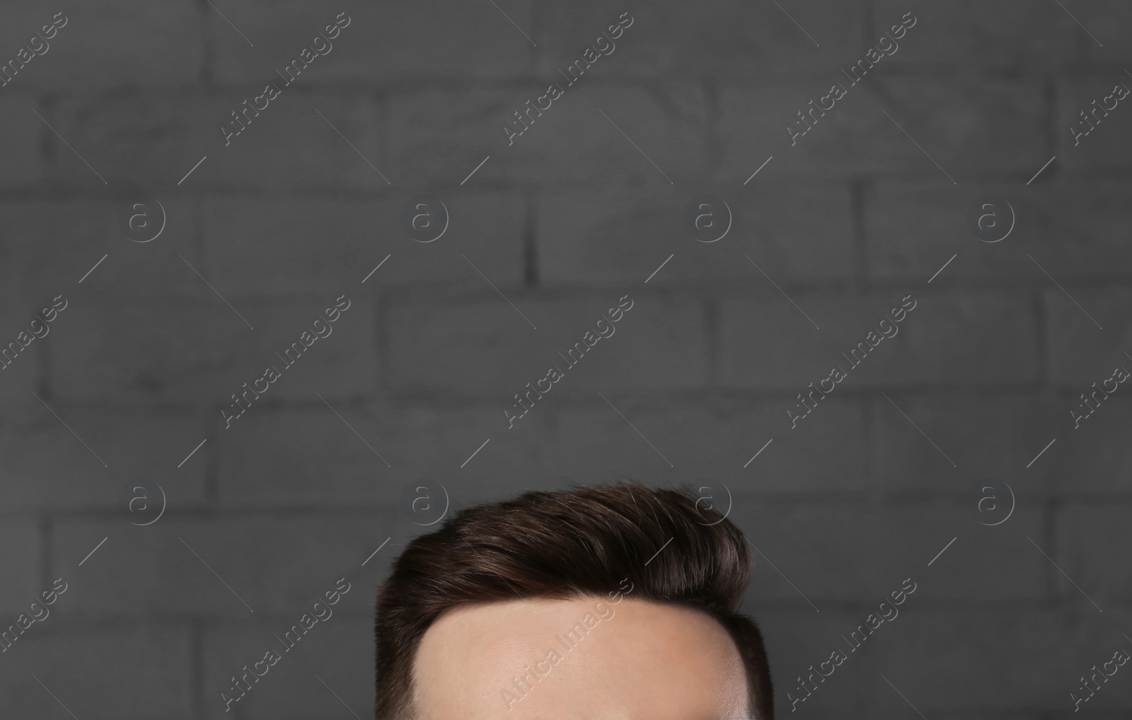 Photo of Man with beautiful hair on brick wall background, closeup