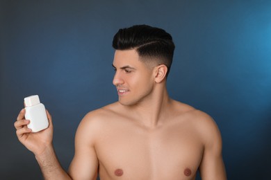 Photo of Handsome man holding post shave lotion on blue background