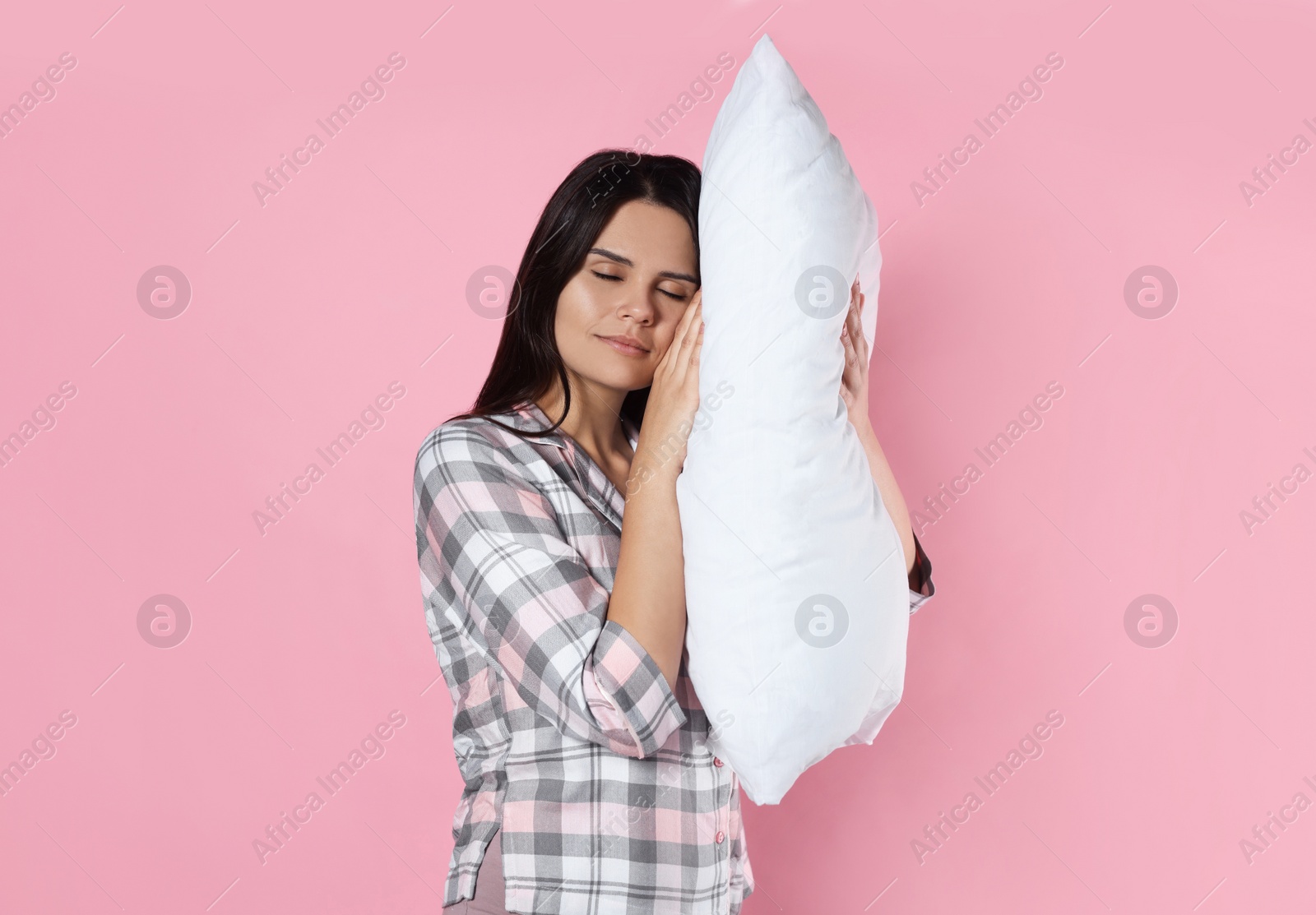 Photo of Sleepy young woman with soft pillow on pink background