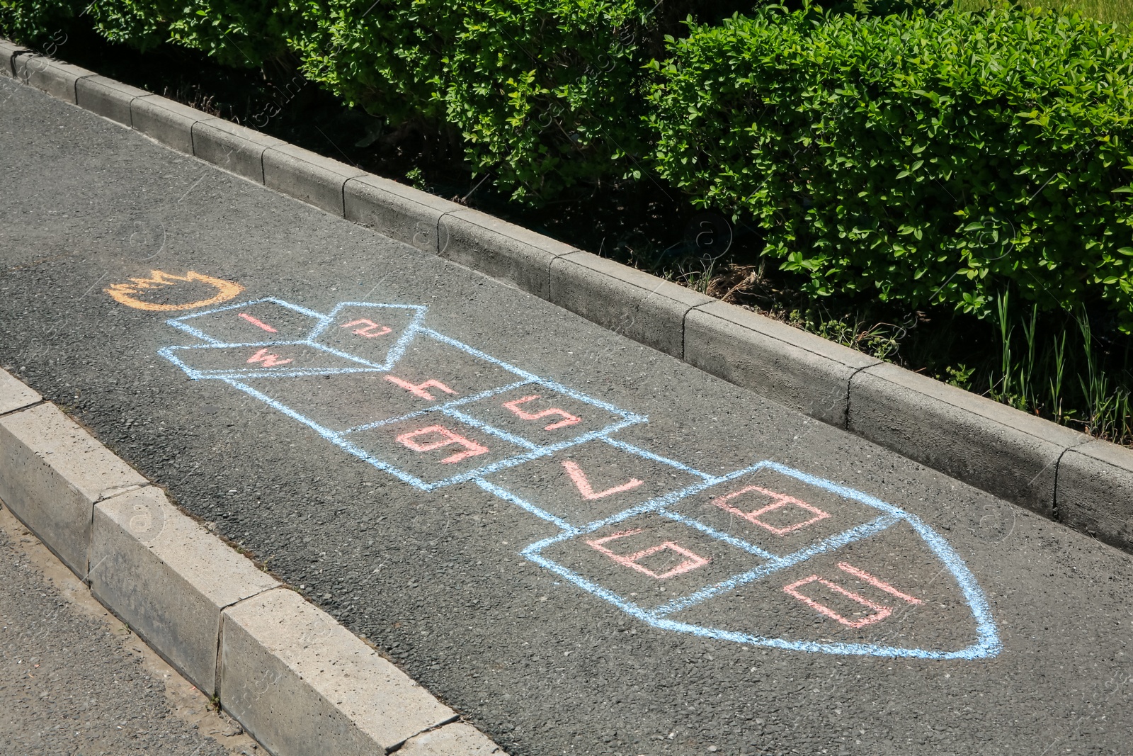 Photo of Hopscotch drawn with colorful chalk on asphalt outdoors