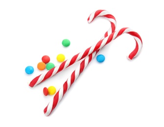 Photo of Tasty candy canes and sweet dragee on white background