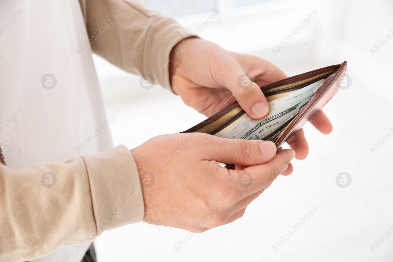 Photo of Man holding wallet with money indoors, closeup