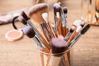 Photo of Set of professional makeup brushes on wooden table, closeup