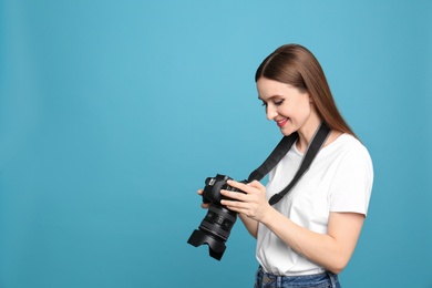 Photo of Professional photographer with modern camera on light blue background. Space for text