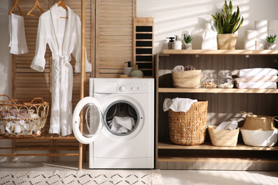 Photo of Modern washing machine and shelving unit in laundry room interior