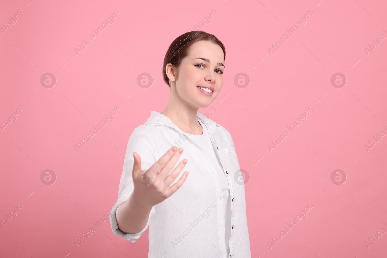 Photo of Happy woman inviting to come in against pink background