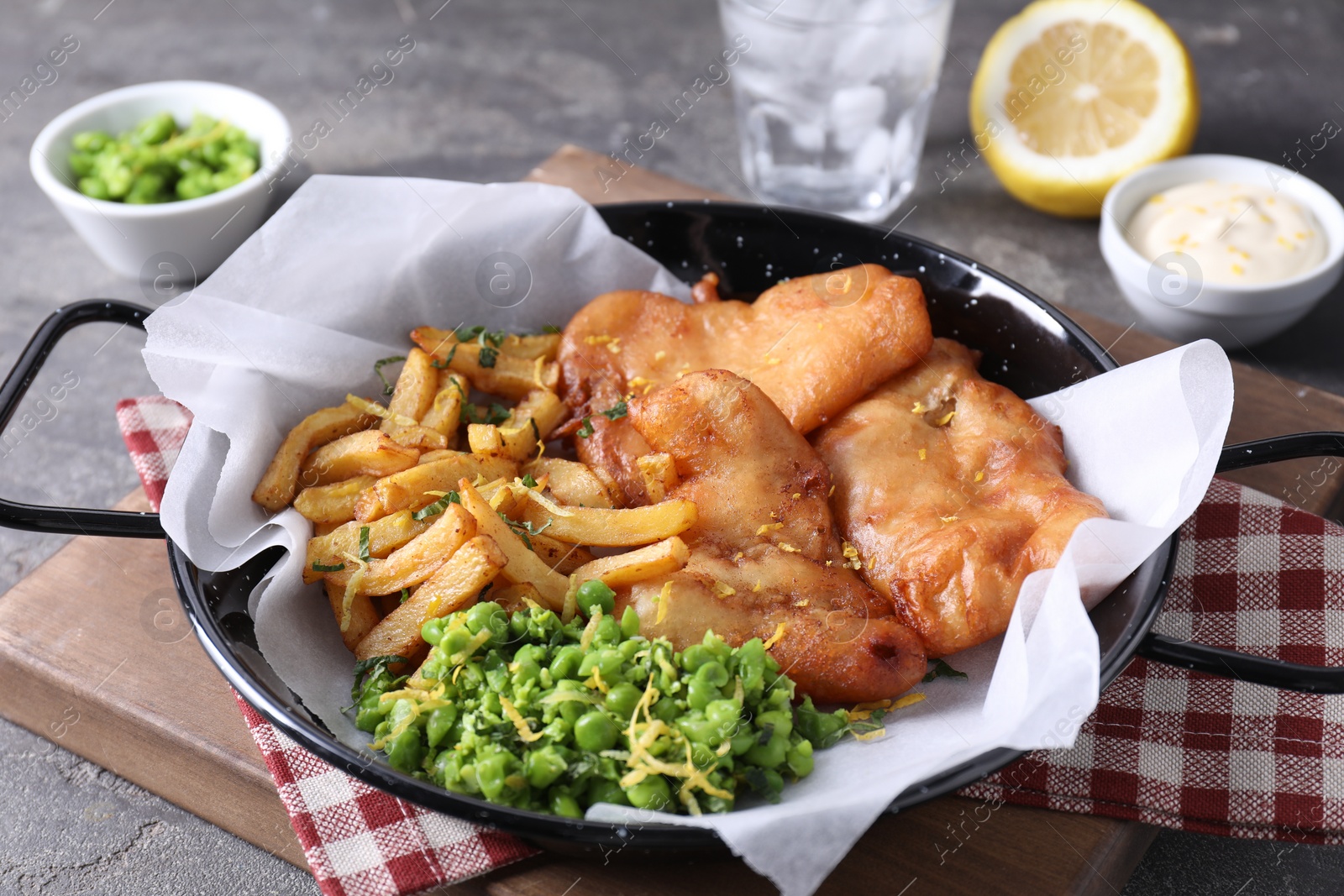 Photo of Tasty fish, chips and peas on grey table, closeup