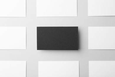 Photo of Blank black and white business cards on light background, flat lay. Mockup for design