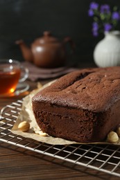 Delicious chocolate sponge cake and nuts on wooden table, closeup