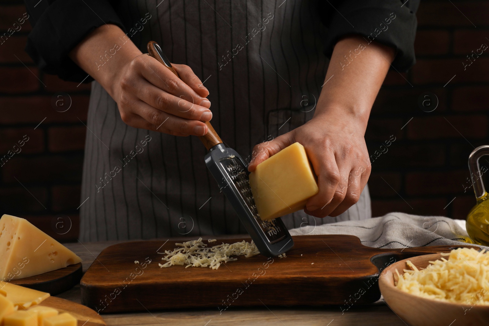 Photo of Woman grating cheese at wooden table, closeup