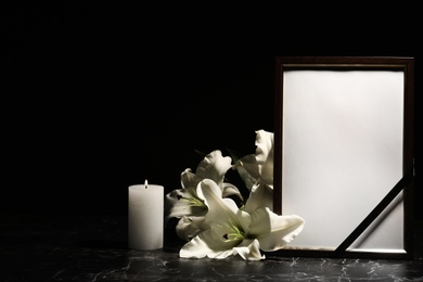 Photo of Funeral photo frame, burning candle and lily flowers on dark background