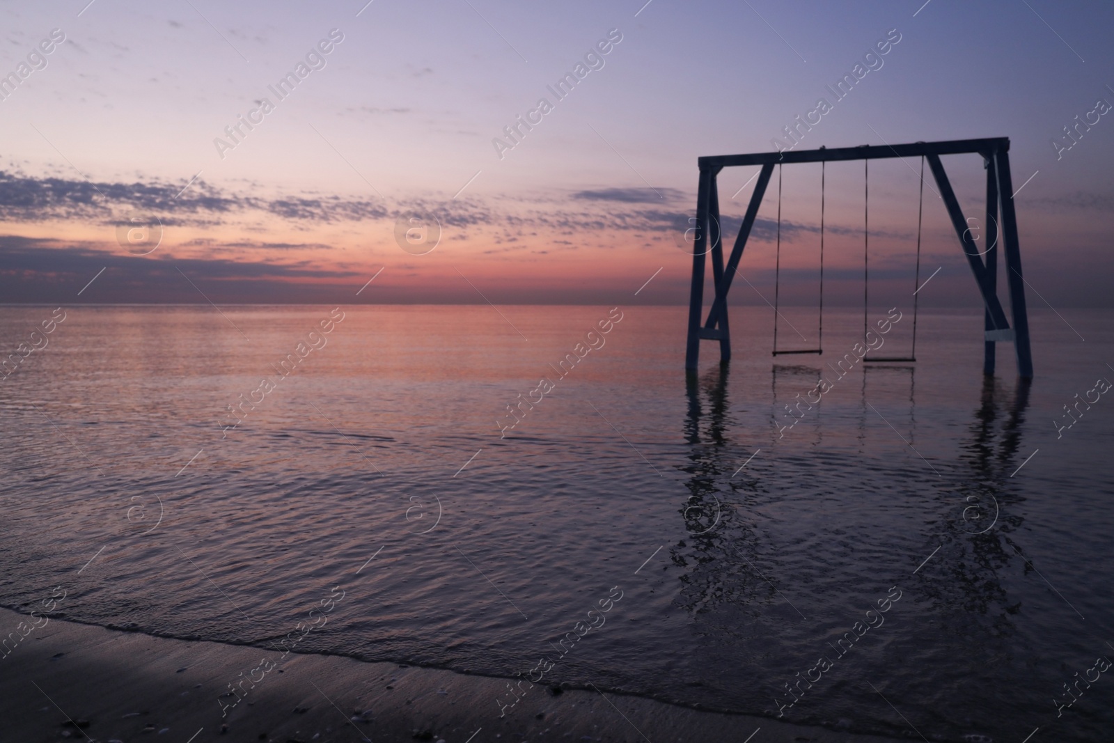 Photo of Picturesque view of swing in water on sunrise