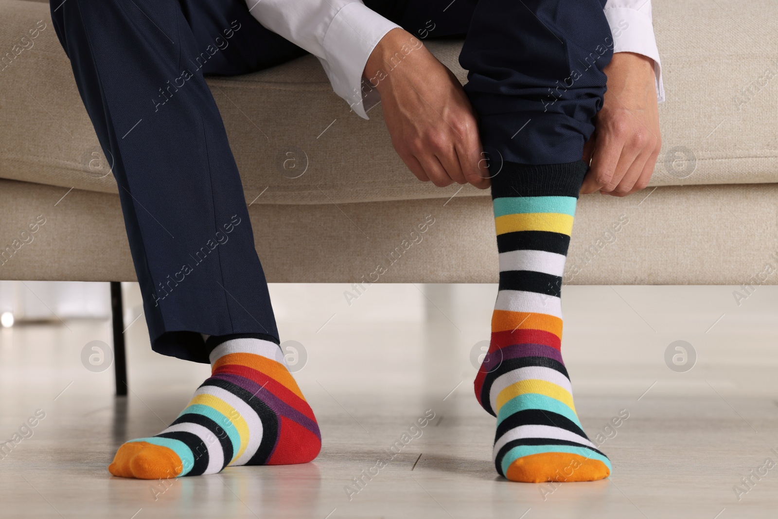 Photo of Man putting on colorful socks indoors, closeup