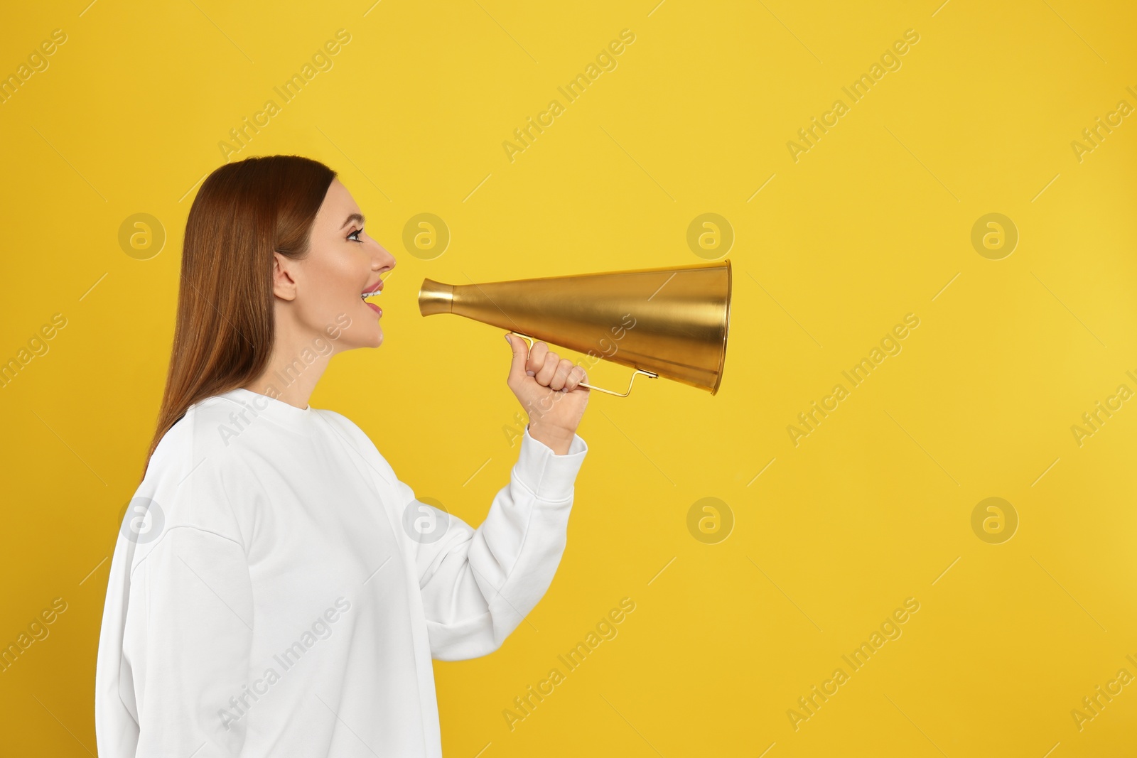 Photo of Young woman with vintage megaphone on yellow background