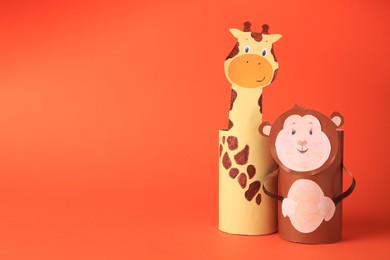 Photo of Toy monkey and giraffe made from toilet paper hubs on orange background, space for text. Children's handmade ideas