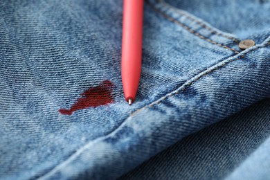 Pen and stain of red ink on jeans, closeup