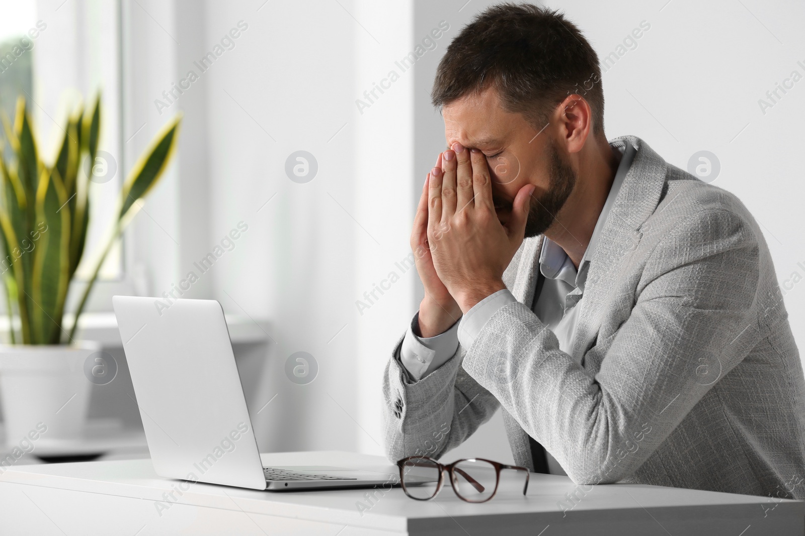 Photo of Man suffering from eyestrain at desk in office