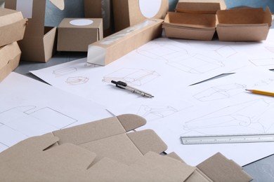 Photo of Creating packaging design. Drawings, boxes and stationery on table, closeup