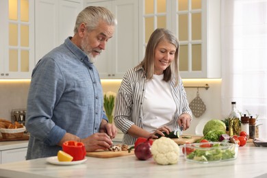 Happy senior couple cooking together in kitchen