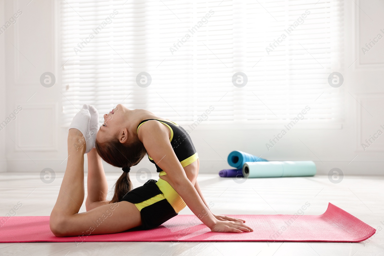 Photo of Cute little girl doing gymnastic exercise indoors