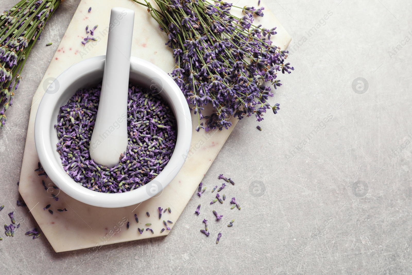 Photo of Top view of mortar and pestle with lavender flowers on grey stone background, space for text. Natural cosmetic