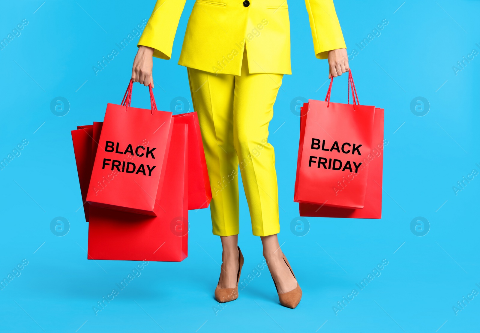 Photo of Woman with shopping bags on light blue background, closeup. Black Friday