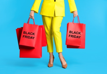 Woman with shopping bags on light blue background, closeup. Black Friday