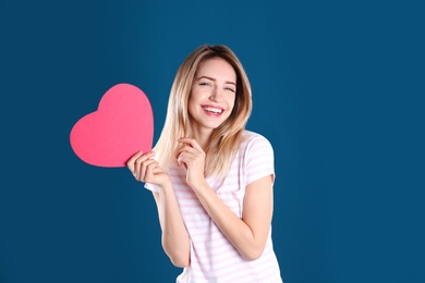 Portrait of pretty woman with heart shaped gift box on color background