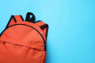 Photo of Stylish orange backpack on light blue background, top view. Space for text