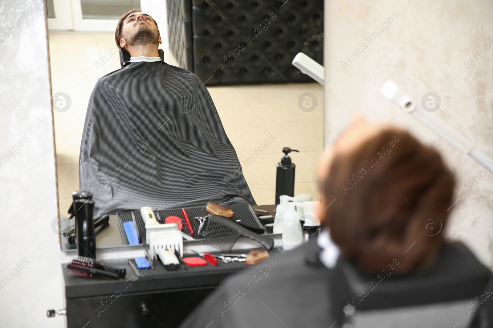 Photo of Young man visiting barbershop. Professional shaving service