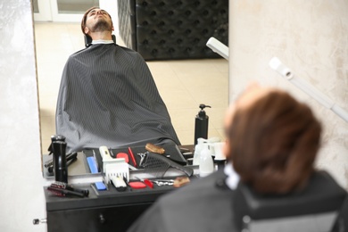 Young man visiting barbershop. Professional shaving service