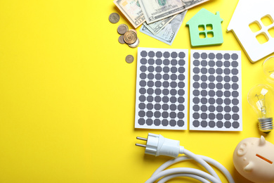 Photo of Flat lay composition with solar panels and piggy bank on yellow background. Space for text