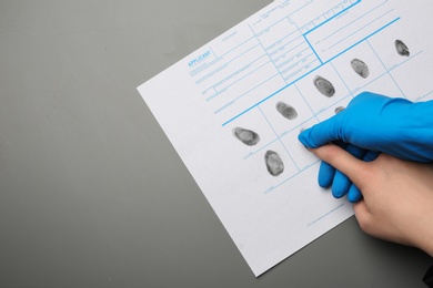 Photo of Investigator taking fingerprints of suspect on grey background, top view with space for text. Criminal expertise