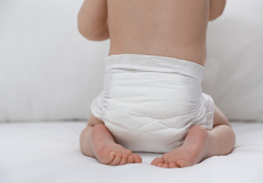 Photo of Cute little baby in diaper on bed, closeup