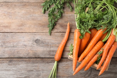 Photo of Crate of fresh carrots on wooden background, top view. Space for text