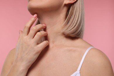 Photo of Woman touching her neck on pink background, closeup