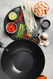 Photo of Flat lay composition with black wok, spices and products on grey textured table