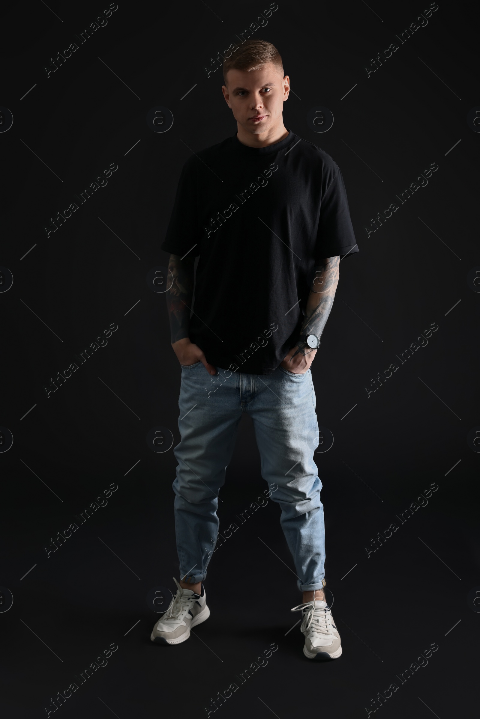 Photo of Young man with tattoos on black background