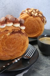 Photo of Round croissants served with coffee on grey table. Tasty puff pastry