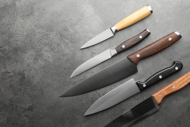 Many different knives on grey textured table, flat lay. Space for text